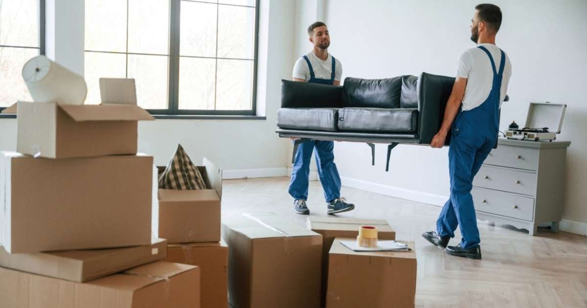 Two movers in Draper UT carrying a couch out of a living room